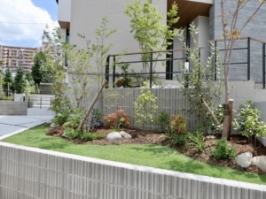 愛知県名古屋市緑区の新築外構工事。アールプランナー（アールギャラリー）住宅。緑化地域の為、植栽や芝生等の緑をふんだんに取り入れ、白の塀やタイルに加え木目調を取り入れてナチュラルな明るい外構に仕上げました。 駐車場にはLIXILのカーポートSCを設置。お庭エリアはウッドデッキと物置・芝生敷きで仕上げました。ファザードデザインに彩りや立体感を持たせるような配置をポイントとした外構デザインです。 ＃ナチュラルモダン　＃施工事例　＃施工実績　＃ミライエエクステリア　＃パートナーホーム　名古屋市名東区・日進店